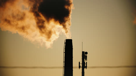 industrial factory pipes silhouette emitting thick toxic smoke into atmosphere