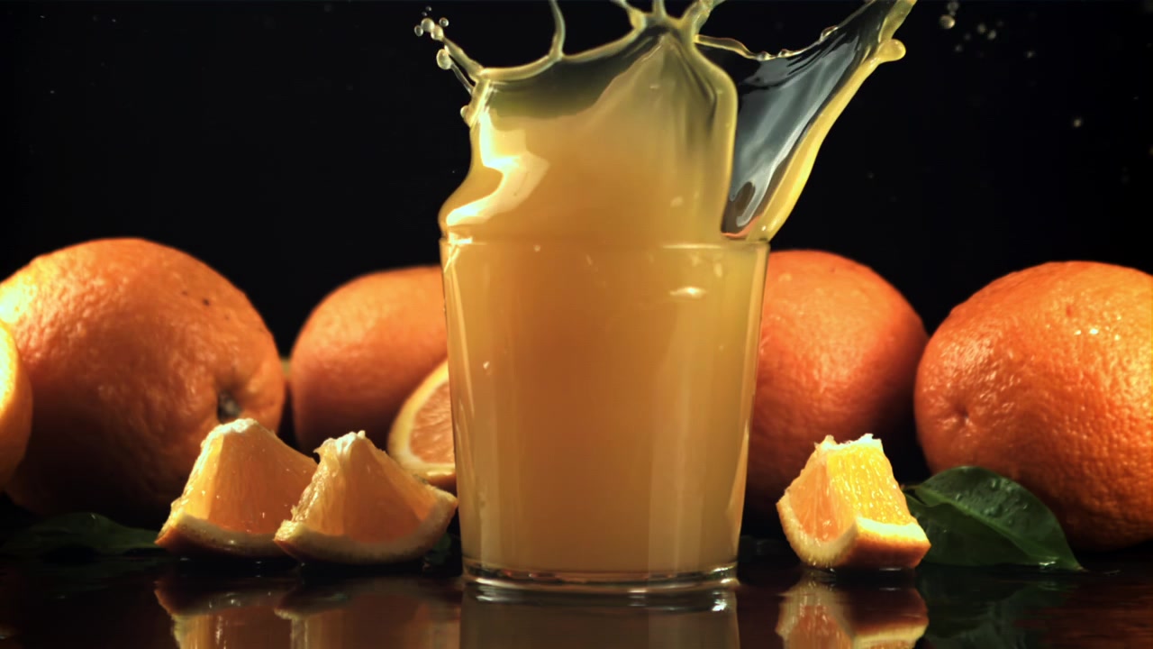 Slow Motion Orange Slice Splashing into Fresh Orange Juice