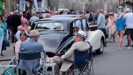 amigos ancianos charlan en un evento de coches antiguos.