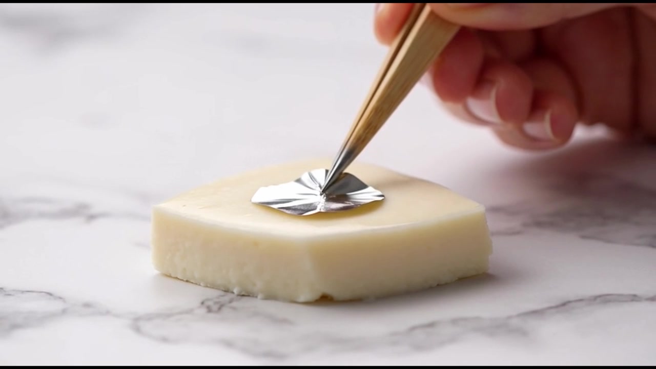 Applying Silver Leaf to a Piece of White Cheese