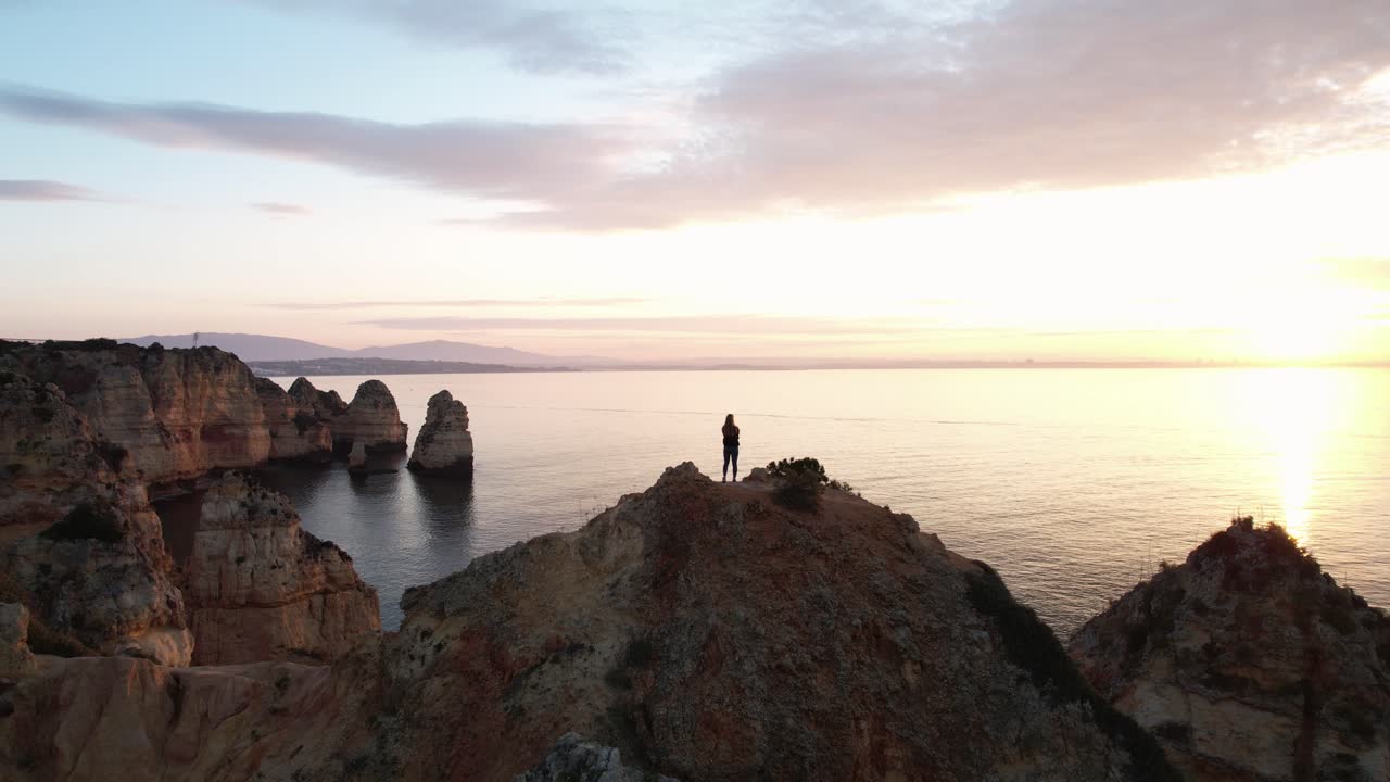 포르투갈 알가르베의 바위가 많은 해안선에서 일출을 보는 사람