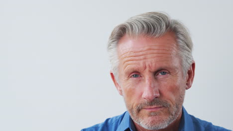 studio shot of serious senior man against white background looking at camera