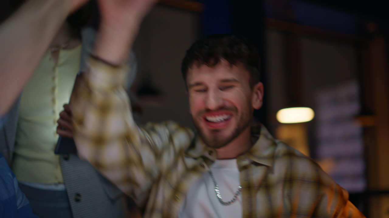 Joyful coworkers celebrating success giving five in evening studio portrait