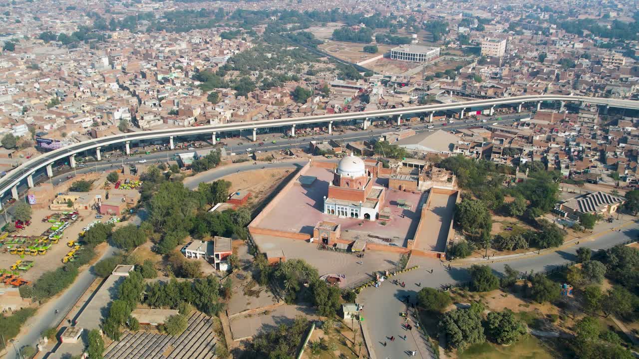 Descending drone view of a shrine in a dense city area during daylight.