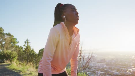 Mujer-Afroamericana-Haciendo-Ejercicio-Al-Aire-Libre-Usando-Auriculares-Preparándose-Para-Correr-En-El-Campo