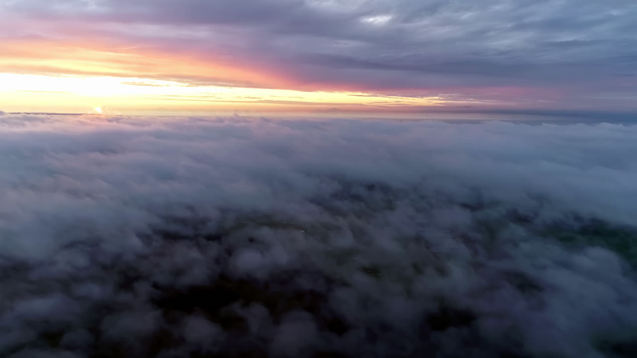 vuelo aéreo sobre el paisaje nublado durante la brillante puesta de sol dorada en el horizonte durante el día nublado - vista desde la ventana del avión