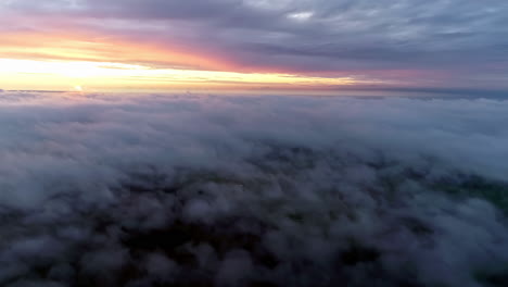 vuelo aéreo sobre el paisaje nublado durante la brillante puesta de sol dorada en el horizonte durante el día nublado - vista desde la ventana del avión