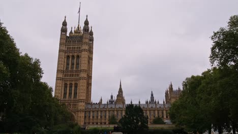 people walk past the victoria tower palace of westminster in the tower gardens south park in london, united kingdom. low wide shot.