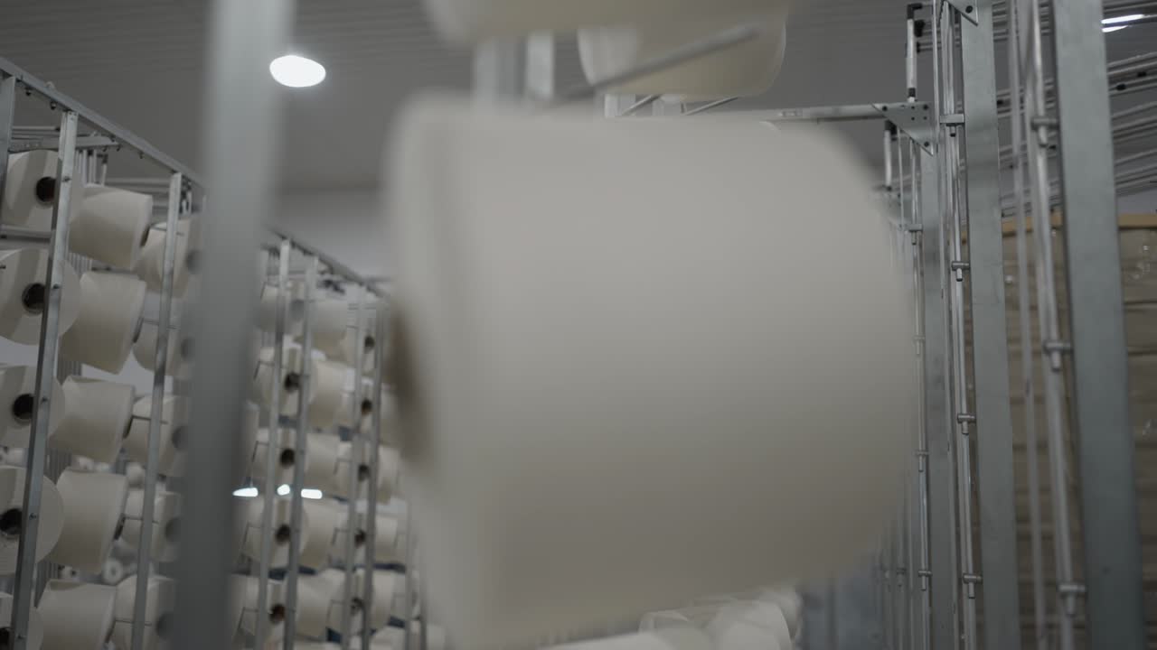 Bobine di filato stoccate su scaffali metallici all'interno di un'azienda tessile industriale