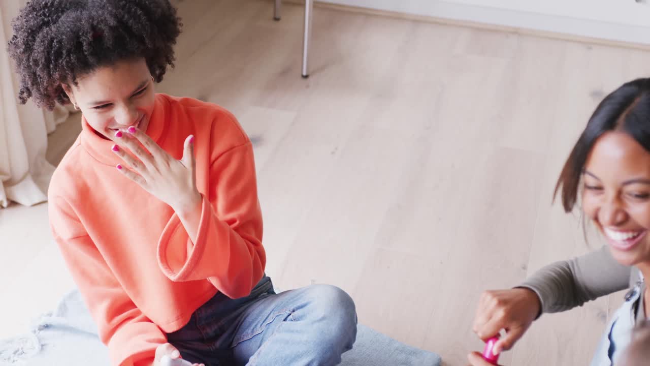 niñas adolescentes felices y diversas amigas pintando uñas en casa, cámara lenta