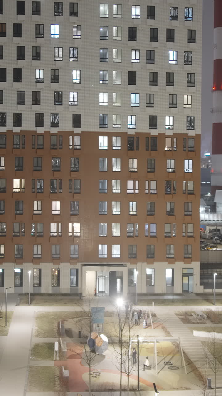 Apartment building at night with illuminated windows and outdoor park