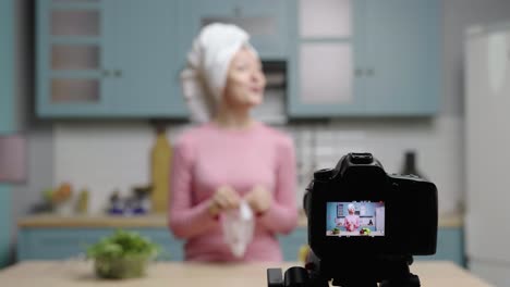 woman demonstrating face mask application in kitchen