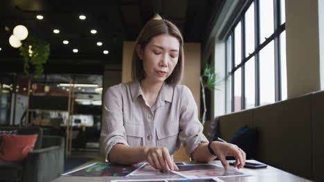 asian businesswoman having a video chat going through paperwork modern office