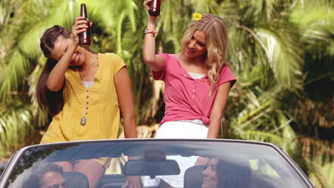 group of friends drinking beer in a convertible car