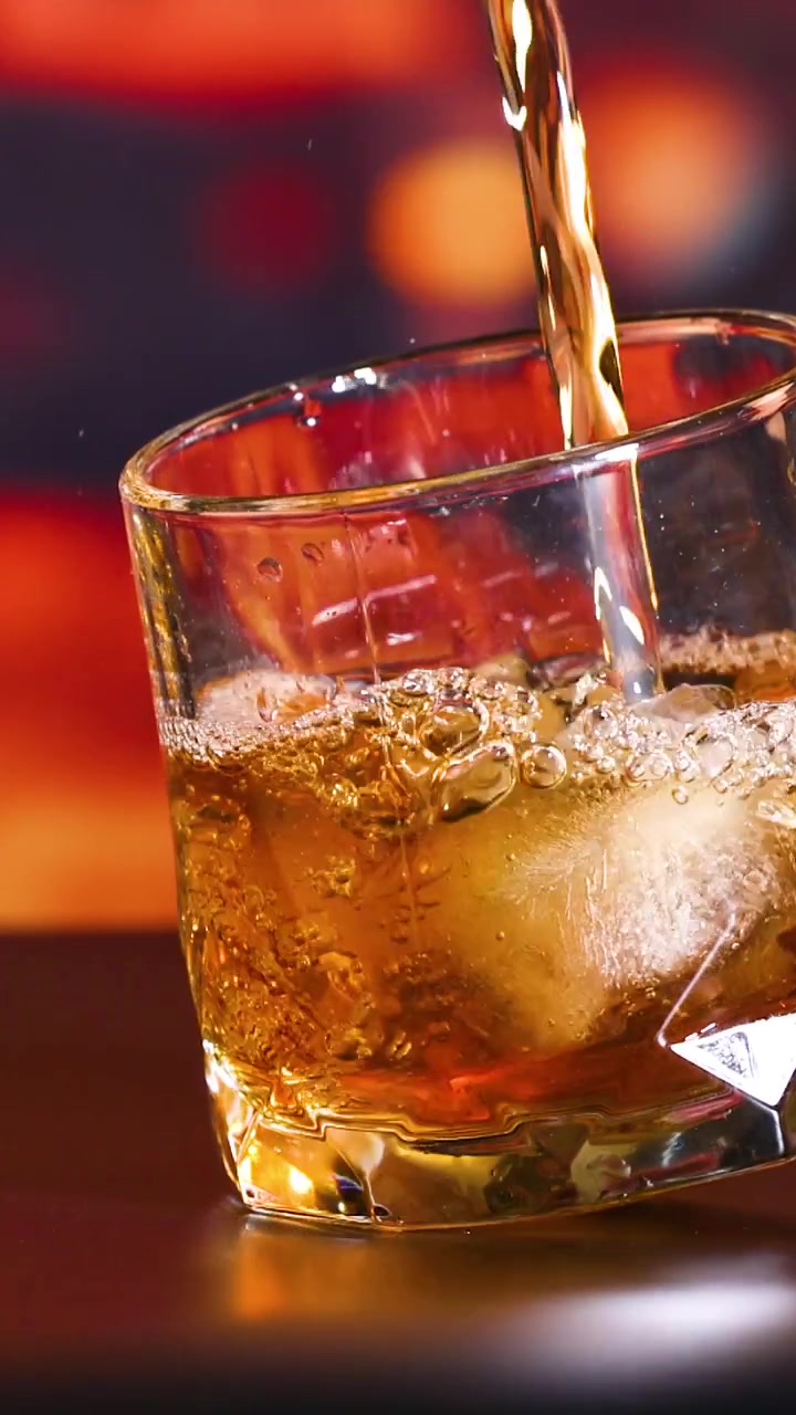 Whisky versato in un bicchiere con ghiaccio