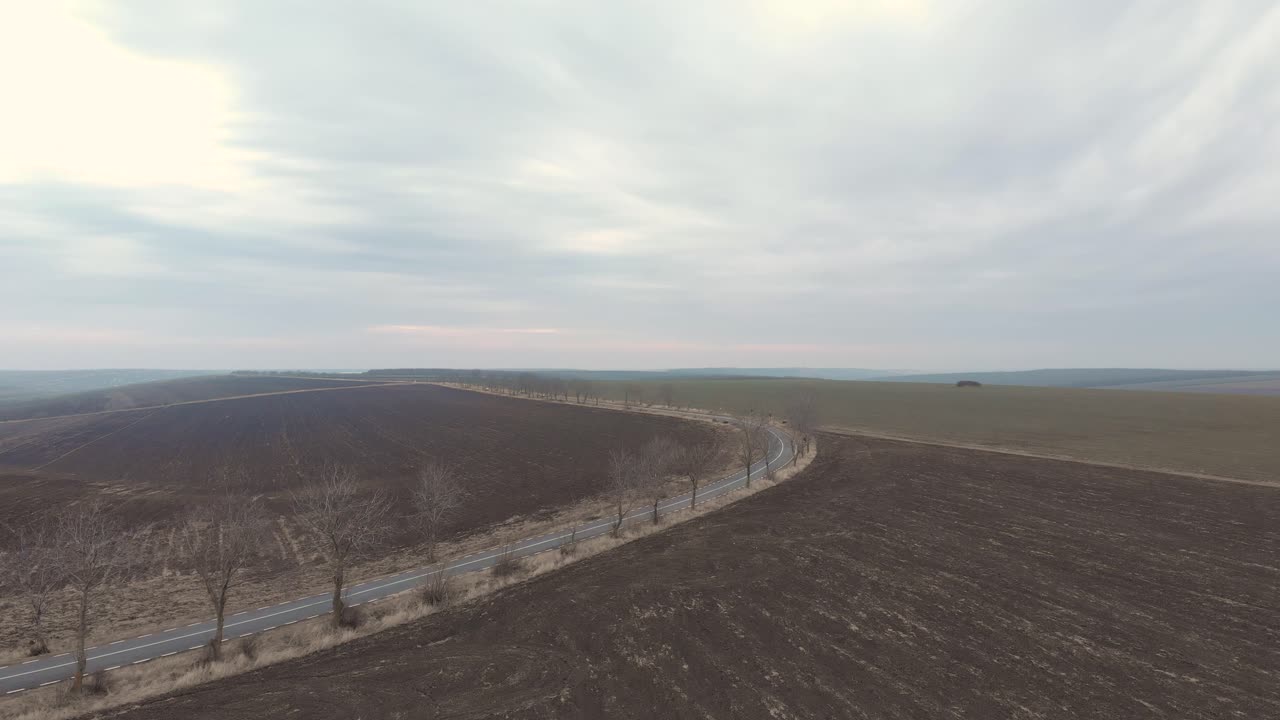 vista de la carretera remota por los campos bajo el cielo sombrío