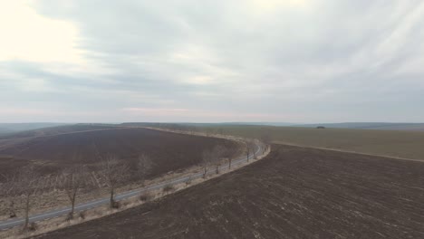 Vista-Of-Remote-Road-By-The-Fields-Under-Gloomy-Sky