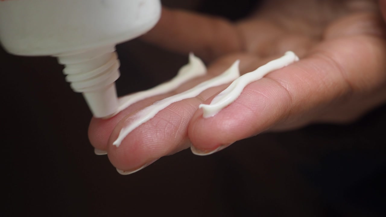 Close-up of Hand Applying Cream from a Tube
