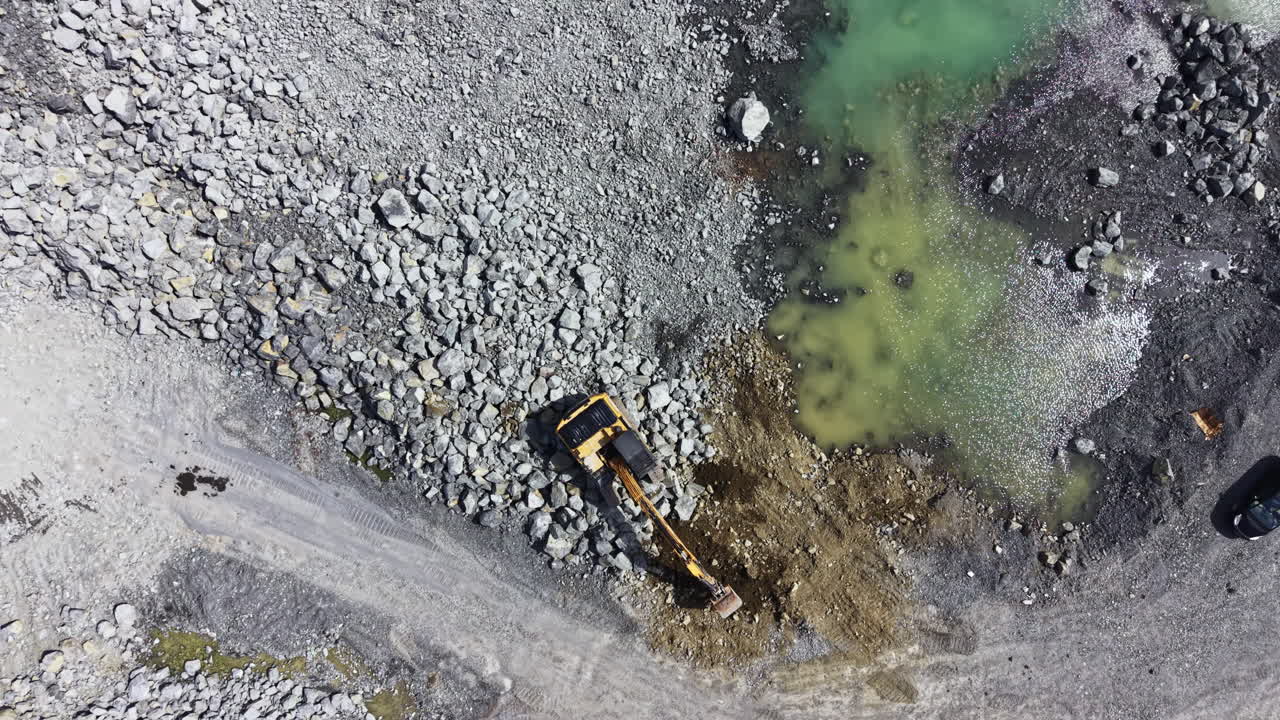 Granite quarry where machines work to extract stone and move materials during bright daylight