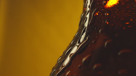 Macro-Shot-Of-Condensation-Droplets-Running-Down-Bottle-Of-Cold-Beer-Or-Soft-Drinks-Against-Yellow-Background