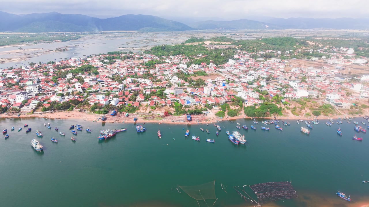 Explore Bien Lo Quang, uma área costeira no Vietnã. Observe barcos de pesca navegando na água e casas visíveis ao longo da costa. Observe a paisagem e as atividades da comunidade