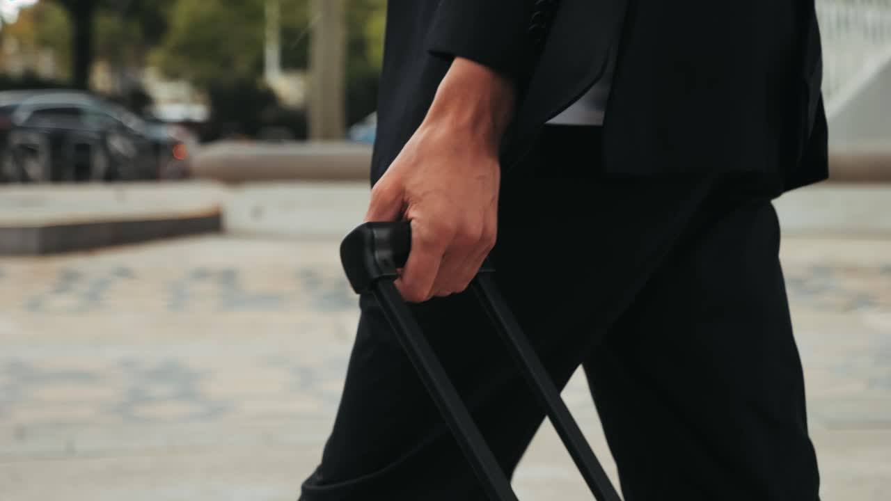 Turista con valigia in Spagna. Un viaggiatore con bagaglio e giacca da completo su una strada commerciale si dirige verso un hotel, un ufficio o un terminal aeroportuale, godendosi l'atmosfera vivace.