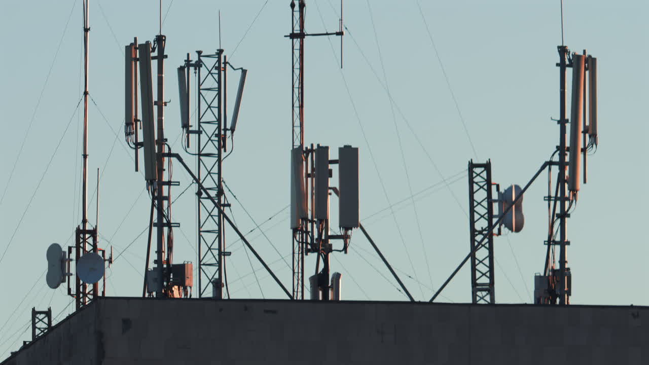 Antennas and communication towers stand on top of a building under the warm morning light