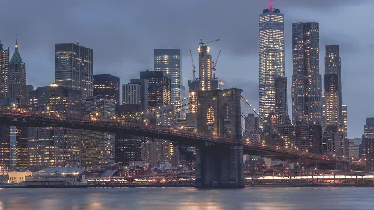Grabación en time-lapse del Puente de Brooklyn y el horizonte del Bajo Manhattan en la Ciudad de Nueva York al atardecer. Las torres de piedra iluminadas y los cables de suspensión del puente contrastan