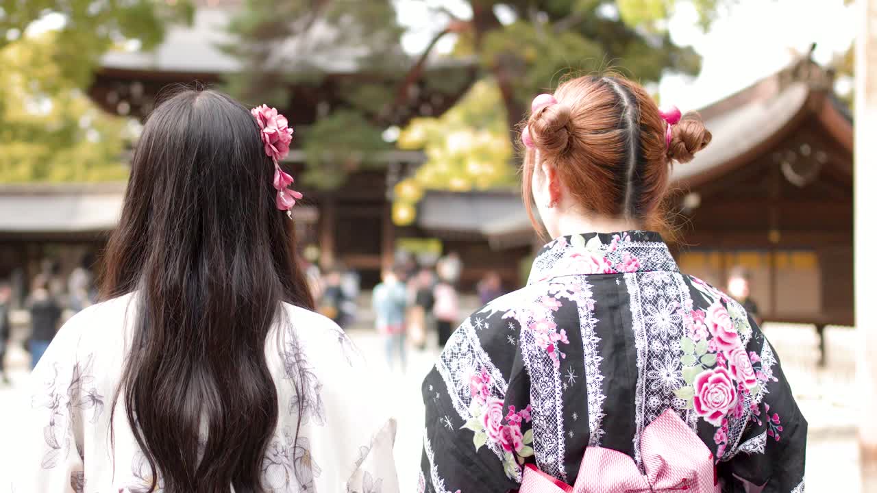 Vue de dos de deux femmes en yukata marchant vers un sanctuaire sous un torii.
