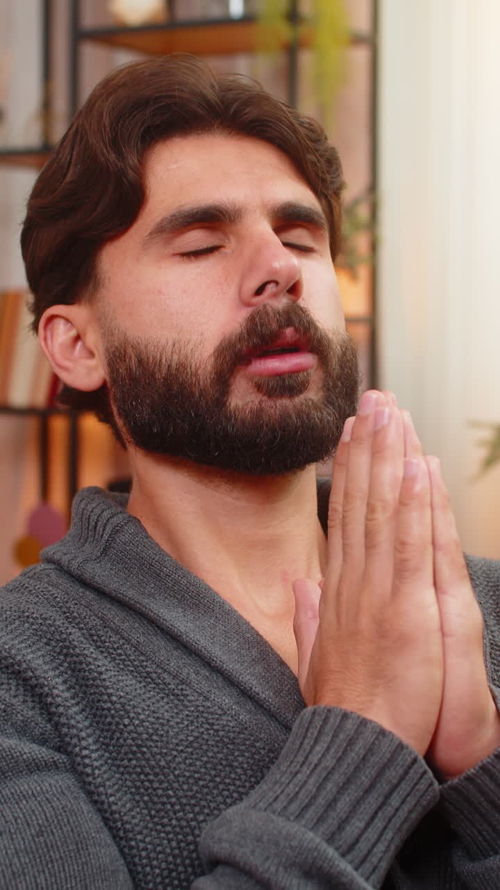Homem indiano de olhos fechados sussurra uma oração, pedindo silêncio, calma, bom humor, paz e esperança, com as mãos gesticulando suavemente.