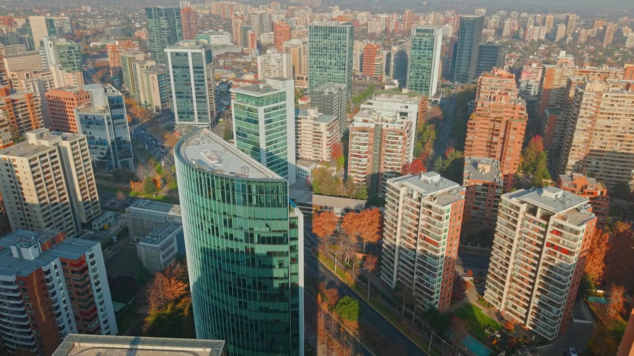 Sobrevoo com movimento de câmera de edifícios modernos de escritórios e residenciais em um dia ensolarado em Las Condes, Santiago, Chile.