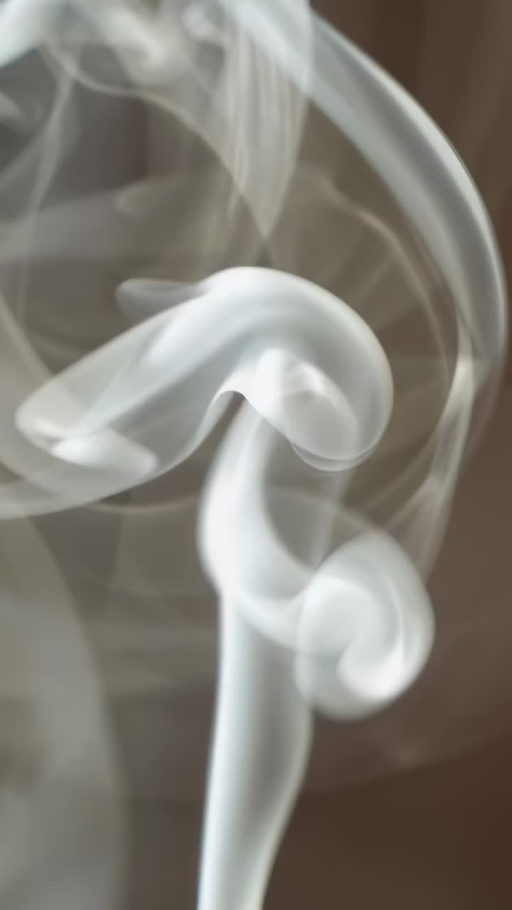 Vertical video: Rising white smoke forming bulb cap looping ribbons in close-up from red stick tip