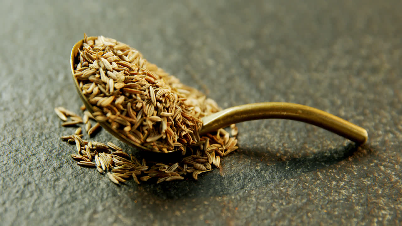 Cumin seeds in spoon on concrete background 4k