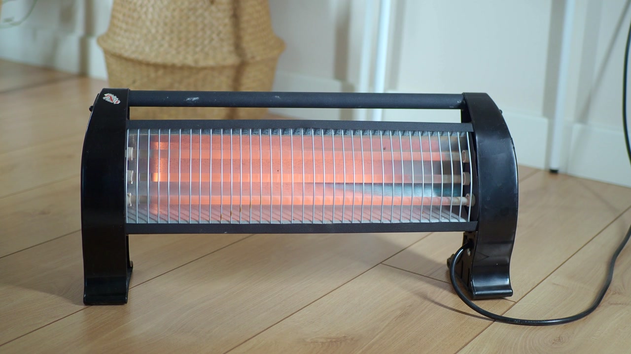 Electric Heater with Glowing Elements on a Wooden Floor