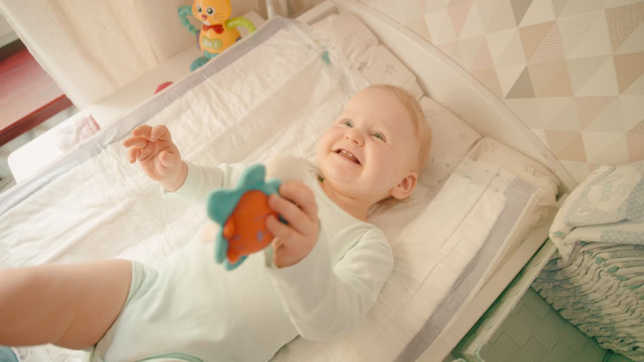 Bambina felice che sorride a casa su un fasciatoio