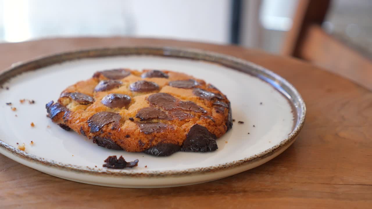 Biscotto con gocce di cioccolato appena sfornato su un piatto bianco.