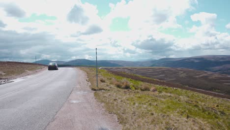 Cars-driving-on-asphalt-road-above-scottish-highlands-on-sunny-day