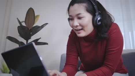 businesswoman redshirt using a tablet with headphone for meeting online at home