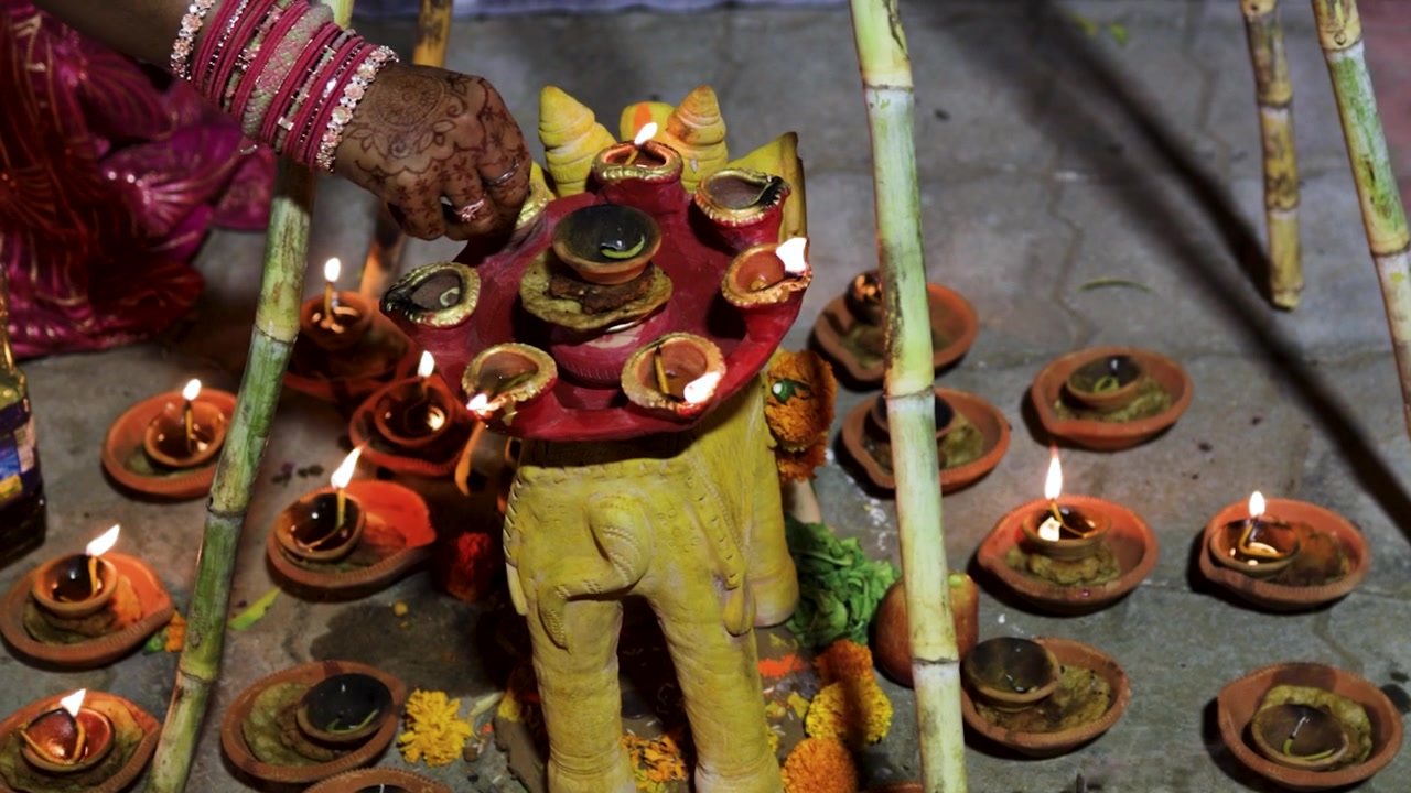 Penataan Chhath Puja Sakral dengan Lampu Minyak Menyala, Buah-buahan, dan Persembahan Tradisional, diambil saat perayaan Chhath Puja suci