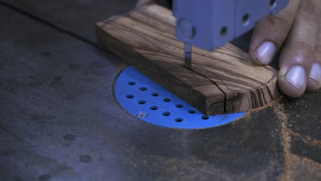 piece of beautiful dark wood being cut by band saw in a delicate and precise fashion