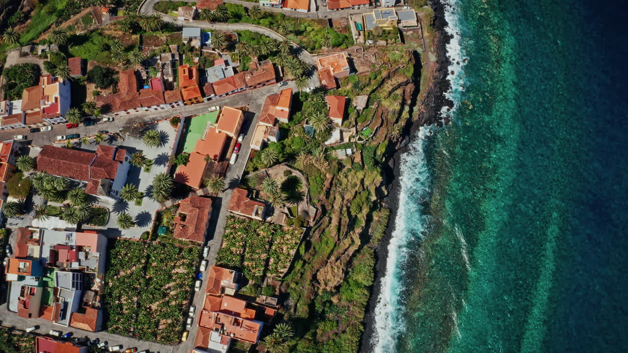 스페인 카나리아 제도 라팔마의 해안선 위에서 찍은 공중 드론. 칠색 바다의 높은 전망, 거친 해안선, 바나나 농장 및 작은 지역 도시. 여름 휴가 목적지.