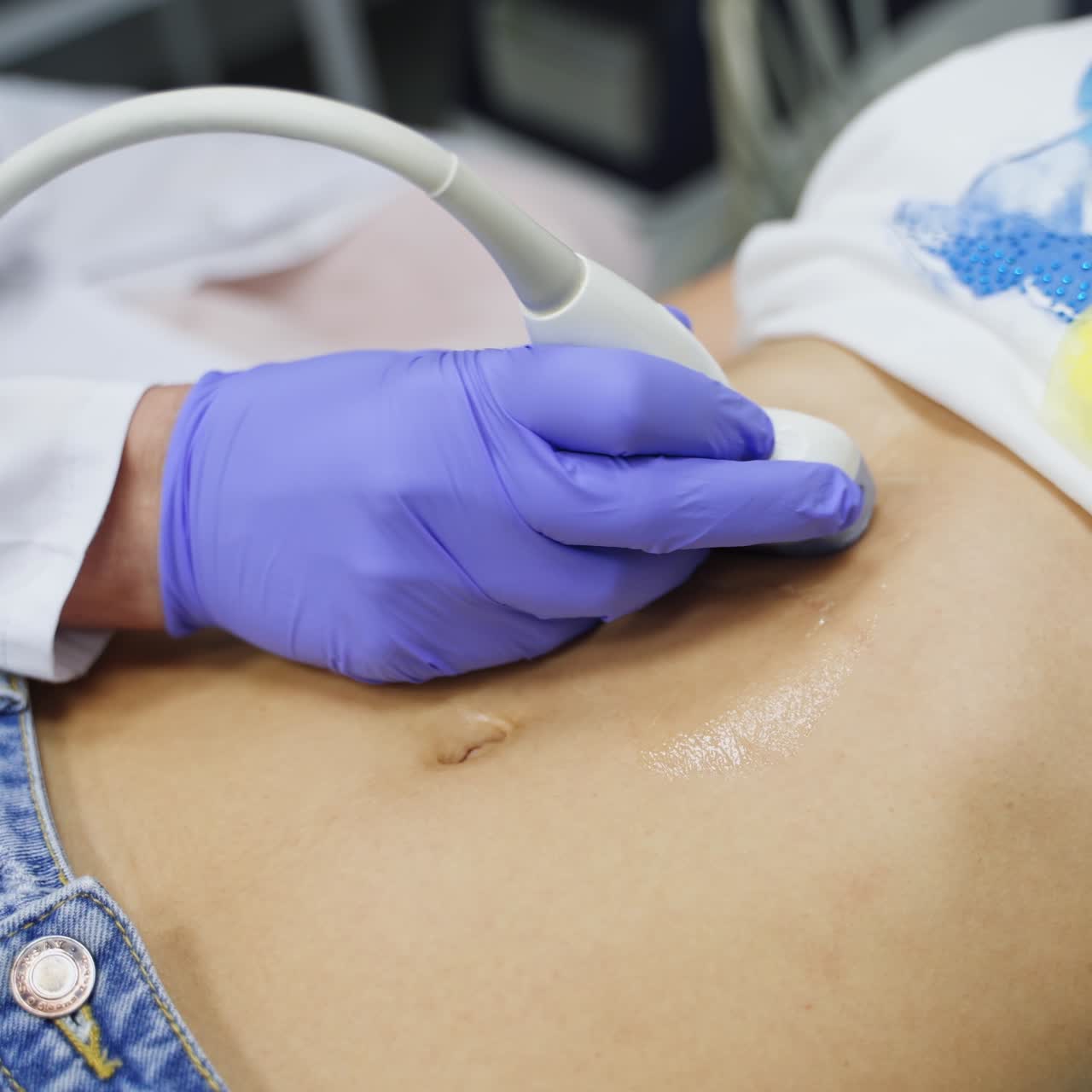 Ultrasound examination of stomach. Gloved hand of a doctor moves the sensor by patient's belly. Close up