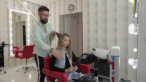 peluquero profesional que trabaja con el cabello de modelo. enderezamiento de hierro corrugado