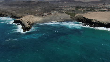 vista aérea en la distancia y en un círculo sobre la playa de la pared y la formación rocosa que está allí, en la isla de fuerteventura en un día soleado