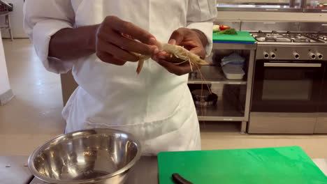 young south african chef prepares raw prawn in commercial kitchen