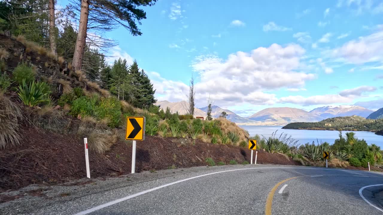 A 9-second timelapse captures a winding mountain road in Queenstown, New Zealand, with lush greenery and clear blue skies