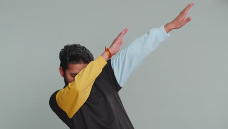 Indian-man-having-fun-dancing,-moving-to-rhythm,-dabbing-raising-hands,-making-dub-dance-gesture