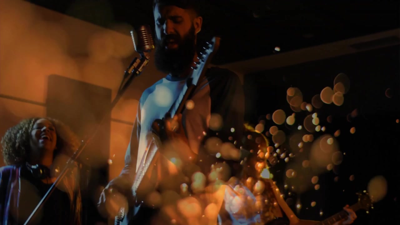 Sfere che si restringono rivelano un chitarrista che strimpella, un bassista che pizzica le corde e un cantante che canta per un concerto musicale