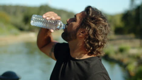 Close-up shot of bearded man drinking water after workout