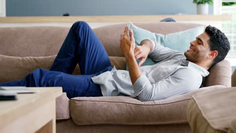 happy man using mobile phone in living room